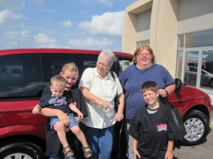 The Riesselman family in front of their red Chrysler Town & Country