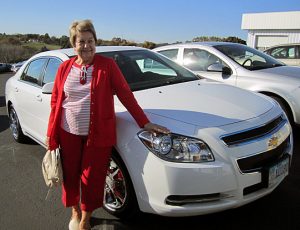 Velma standing beside her new Chevy Malibu sedan