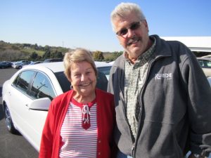 Velma and her salesman in front of her white Chevy Malibu sedan