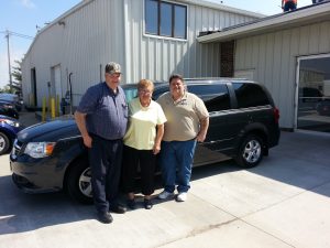 Runde Auto Group customers pictured with their salesman in front of their new Dodge Grand Caravan