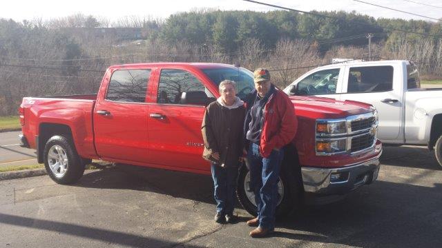 Duane and Linda Huber standing in front of their new red Silverado crew cab at Runde Chevrolet