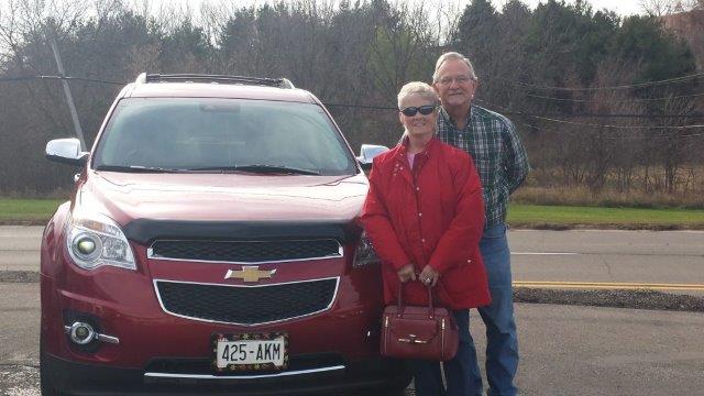 Herman & Carole Dodson posing beside their red 2015 Equinox