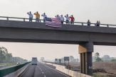 People saluting the buses from an overpass