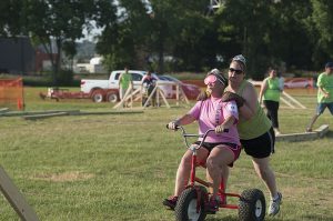 person pushing another person on a tricycle