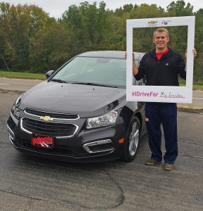 Benjamin holding an i drive for picture frame beside his Chevy Cruze