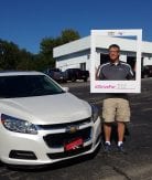 customer standing beside a white Chevy Malibu