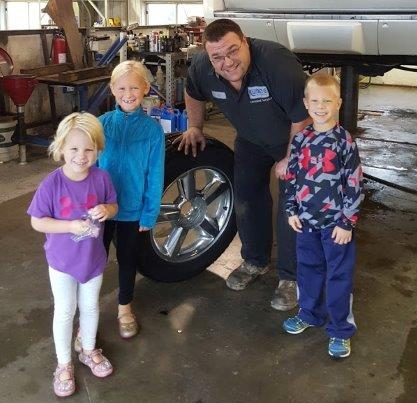 Children from Dubuque watching Al Gassman perform an oil change