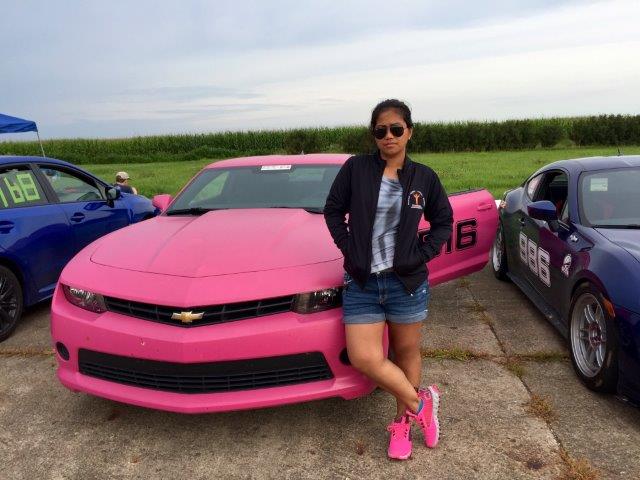 Liza standing in front of her pink Chevy Camaro