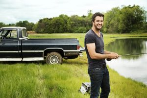 Luke Bryan standing next to a Chevy full-size truck