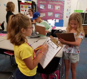 East Dubuque elementary school kids walking around in classroom with clipboards